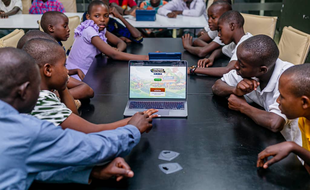 Children gathered around a tablet playing Faunda